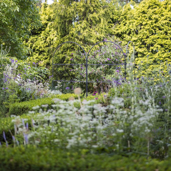 Trio of agriframes versatility screens amongst a large, floral garden 