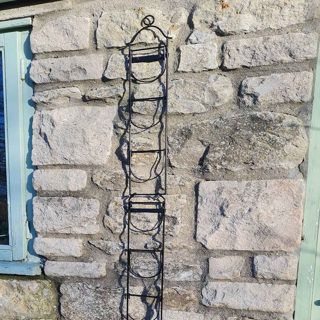 Metal plant trellis against a stone wall