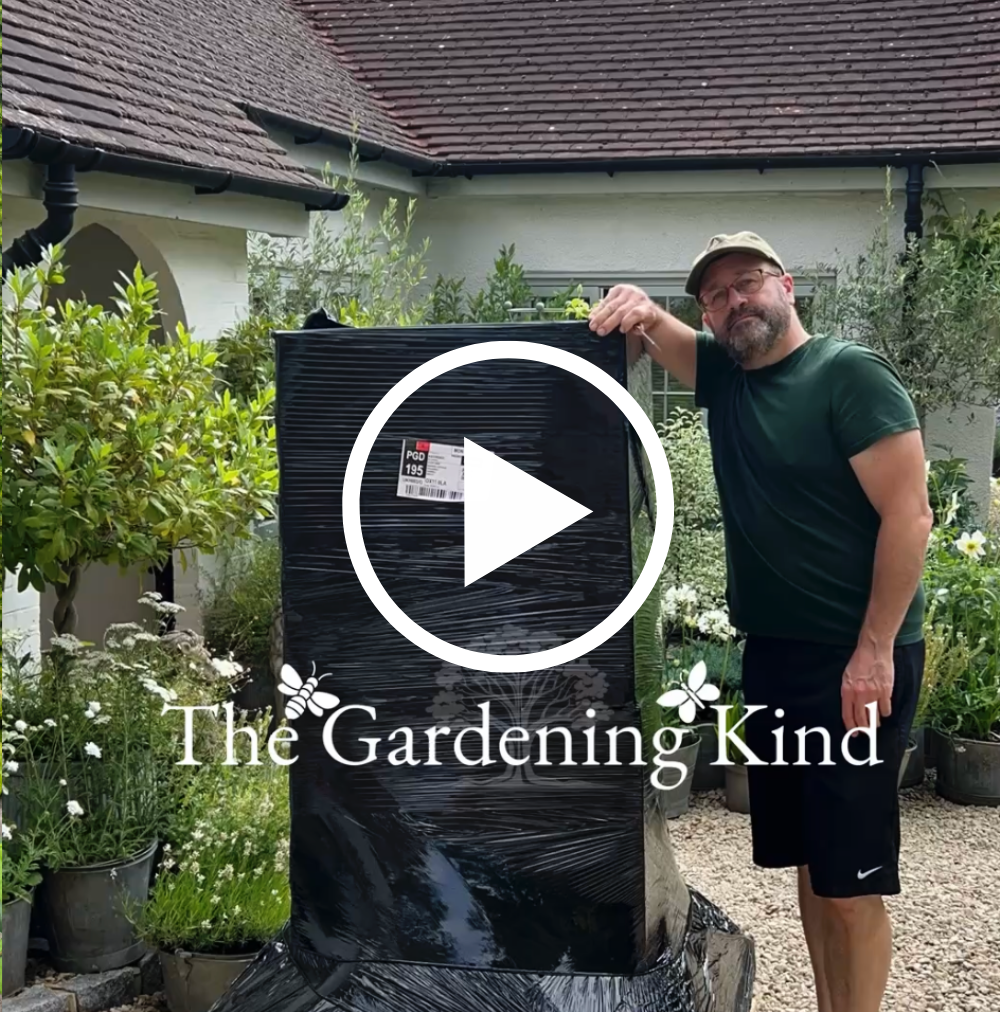 Man holding a large black gardening product with 'The Gardening Kind' branding in a garden setting.