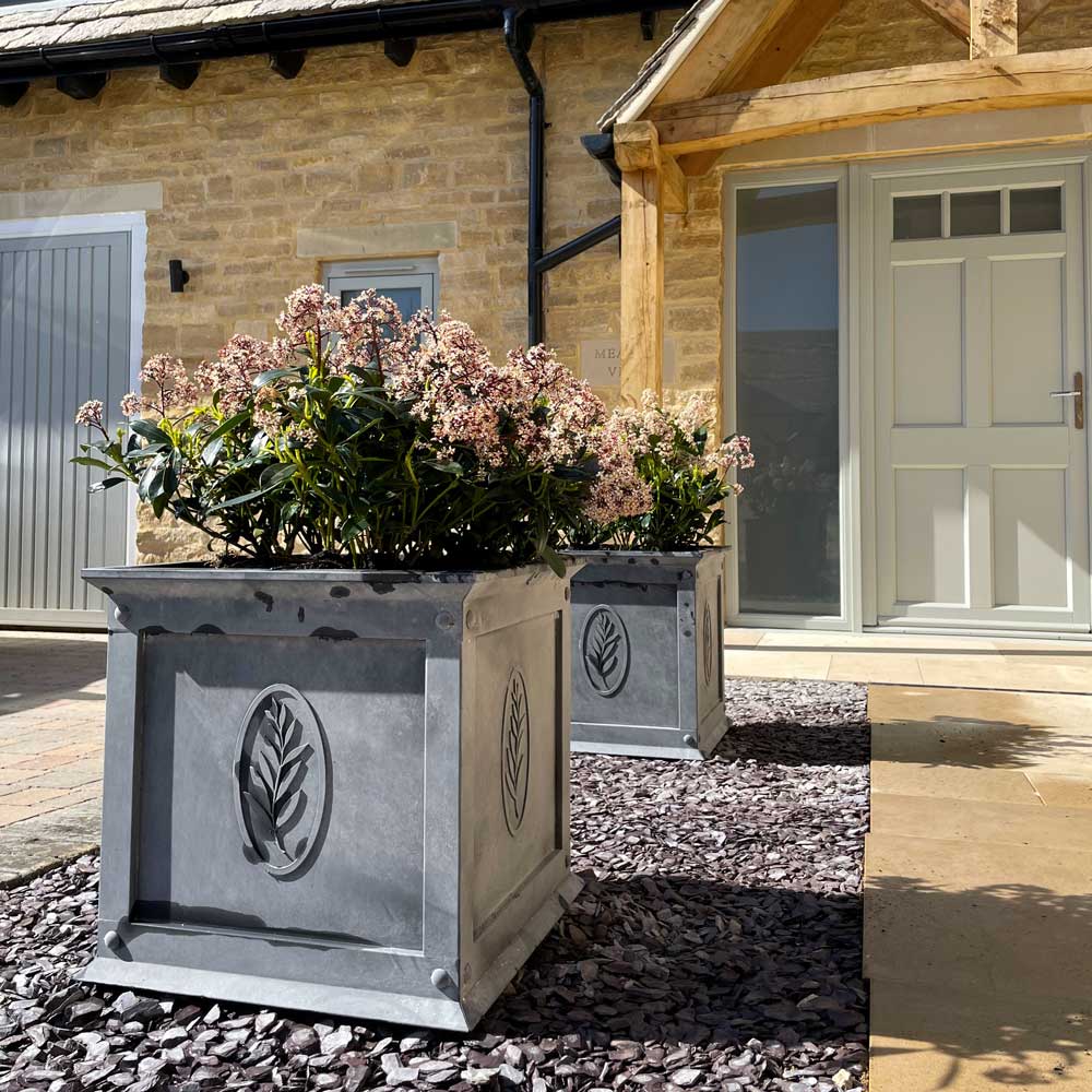 Decorative metal planters with flowers in front of a house.