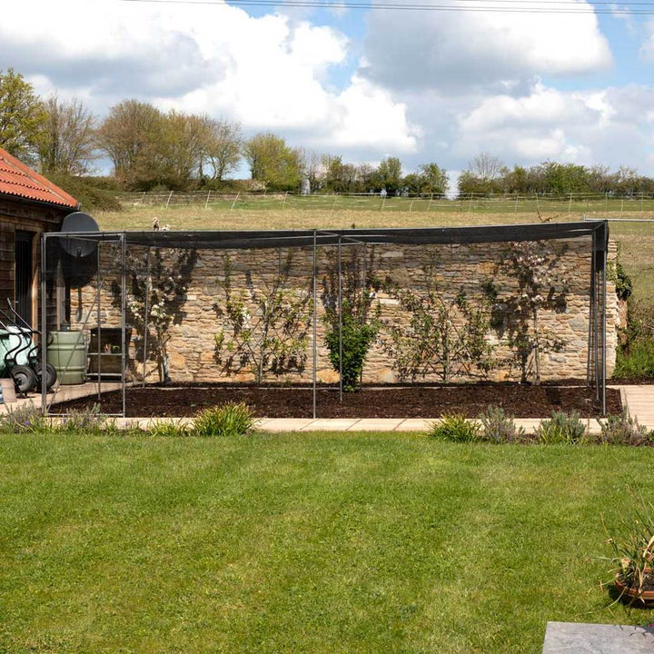aluminium walk in fruit cage containing a soil patch in a garden