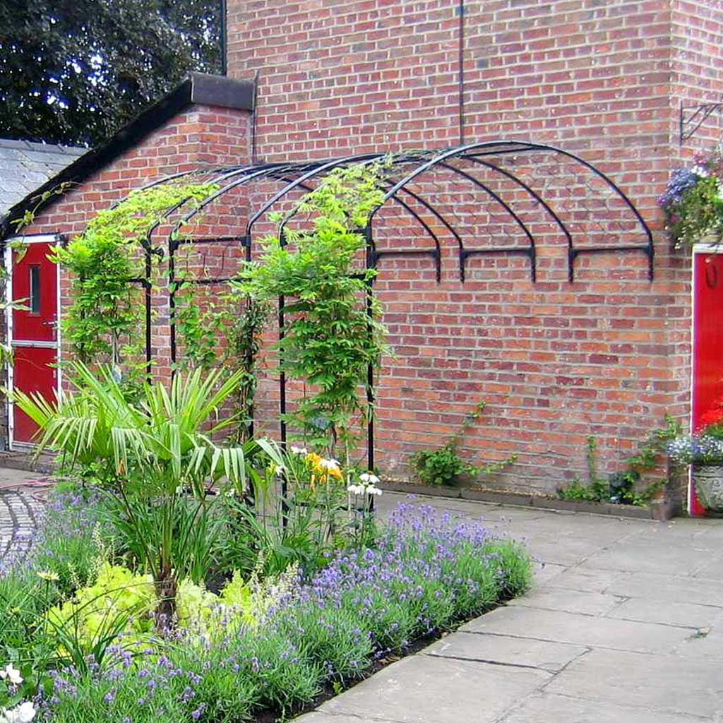 Wall Arch with flowers growing up against a red brick wall